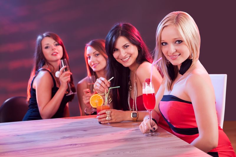 在夜总会的桌子上坐着喝鸡尾酒的女朋友们正在享受一个夜晚