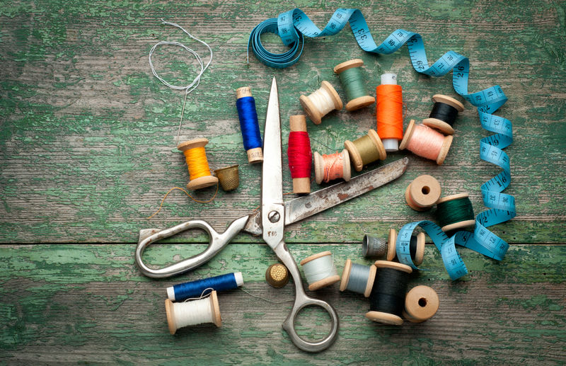 带缝纫工具和彩色胶带/缝纫工具的复古背景-旧木背景上的剪刀、线轴和针