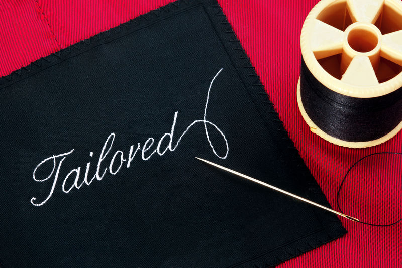 一张衣服标签的照片-上面的字是用针和线轴在红色丝绸衬里上裁剪的