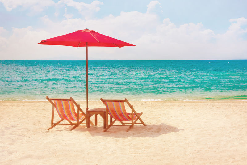 沙滩上的两张躺椅和一把遮阳伞