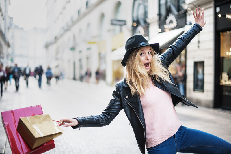 一位年轻时髦的妇女在城里购物-她用欢笑来表达自己的快乐