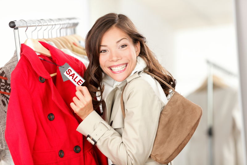 一位购物妇女兴奋地在服装店的服装销售处展示价签-笑容可掬的女人-价格标签上写着减价