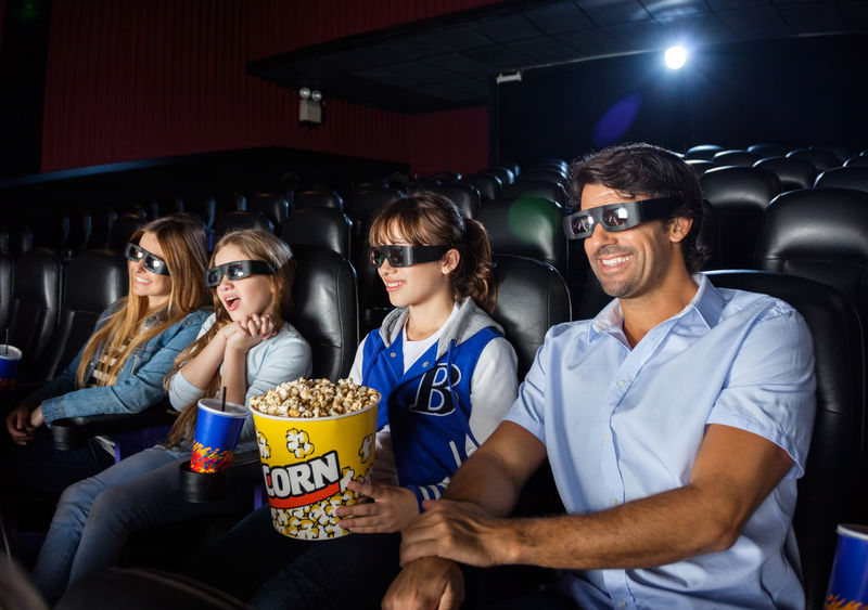 一家四口在电影院边看3D电影边吃零食