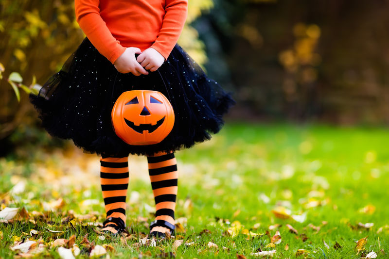 女巫服装在秋天公园玩的小女孩-孩子们在万圣节玩得很开心-孩子们捣蛋-带南瓜灯的蹒跚学步的孩子-孩子们带着糖果桶在秋天的森林里