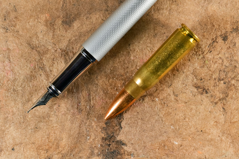 钢笔和子弹在复古背景上的平行位置