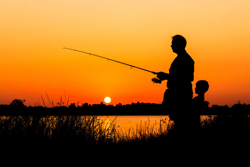 父子在河里钓鱼日落的背景