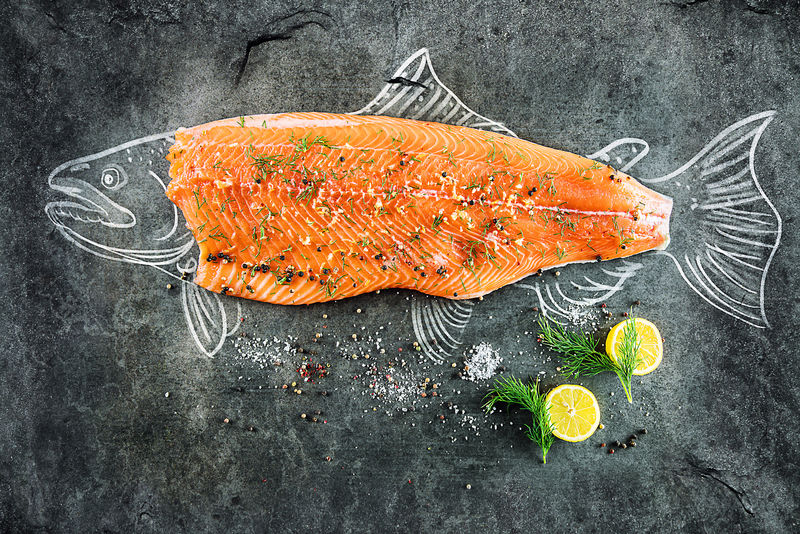 生的三文鱼鱼排，加上柠檬、胡椒、海盐和莳萝，在黑板上画上鲑鱼和牛排的图片。