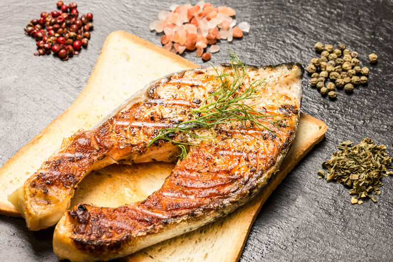 烤三文鱼鱼片配热面包片和石板上的香料