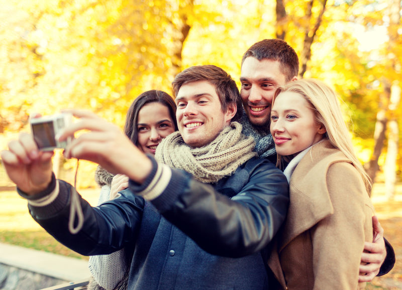 关系、季节、友谊、科技与人的概念——秋园数码相机自拍微笑男女群