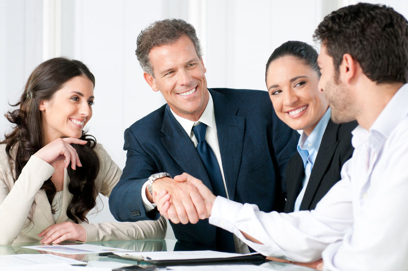 一个成熟的商人在一个现代化的办公室里与他的合伙人和同事握手以达成协议
