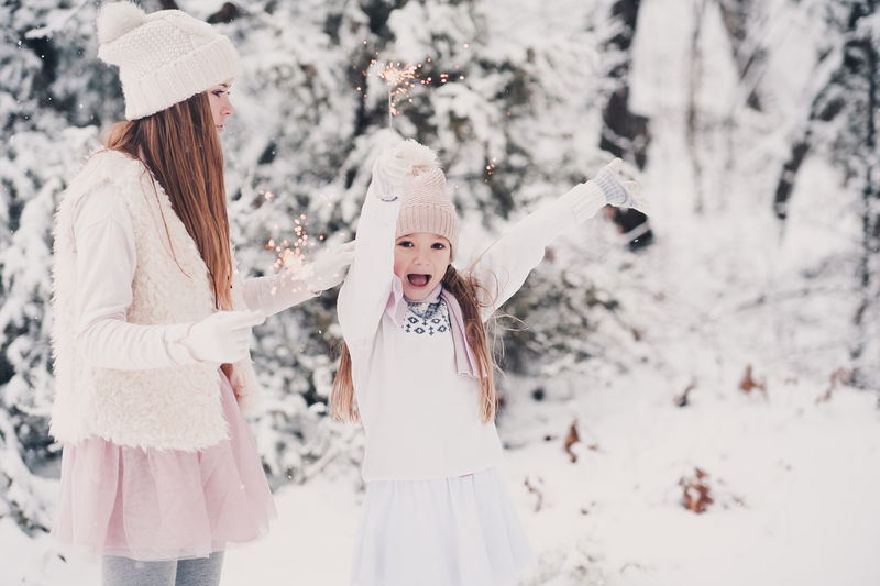 快乐的小女孩在雪天户外玩得开心。玩火花。童年。
