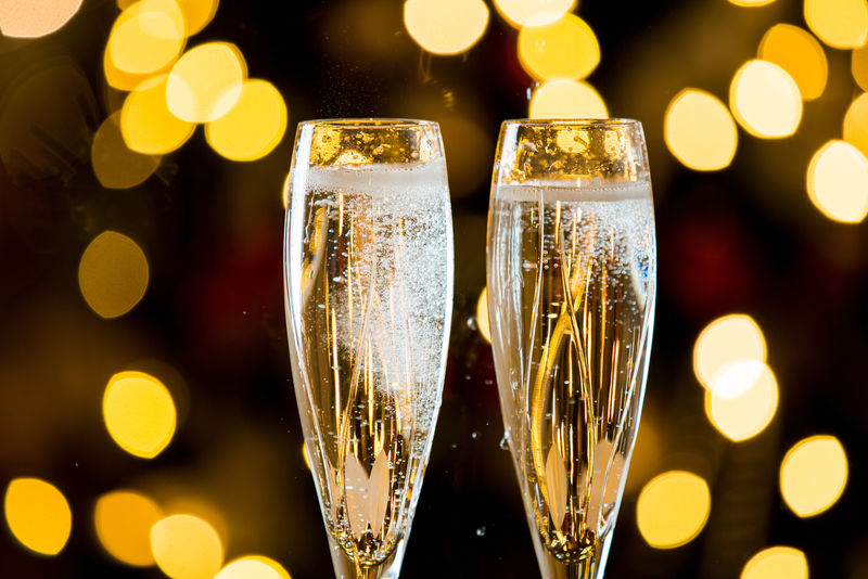 背景是两杯香槟-云杉枝上的红色桌布-客厅装饰有灯光、蜡烛和圣诞树