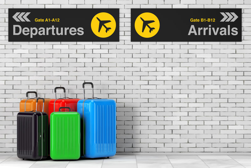 航空旅行概念-砖墙前机场离港和到港信息面板附近的大型多色聚碳酸酯行李箱-三维渲染