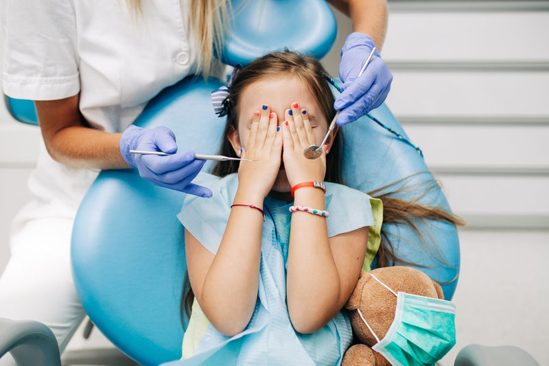 可爱的小女孩坐在牙科椅上接受牙科治疗