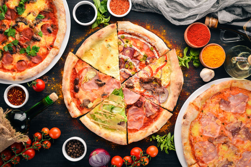 一套意大利披萨-意大利菜-在黑色木质背景上-免费复印空间-俯视图