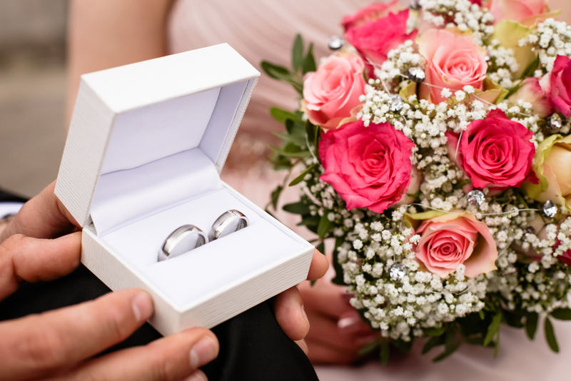 新郎一手拿着结婚戒指盒-一手拿着花束