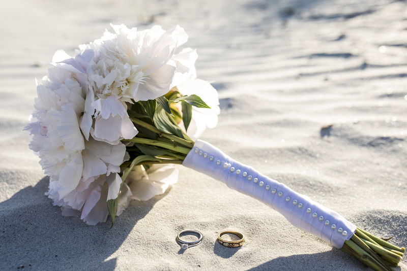 海滩上的结婚戒指和牡丹花束