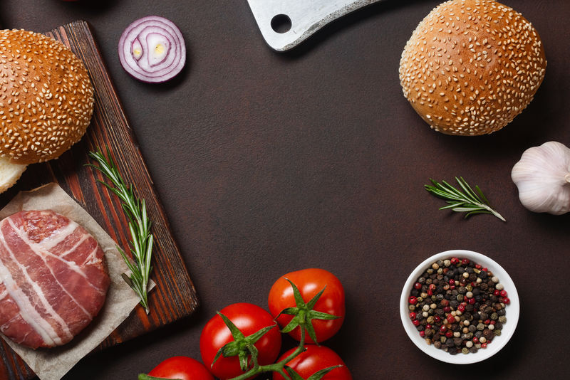 汉堡原料生肉片-番茄-生菜-面包-奶酪-黄瓜和洋葱在生锈的背景上-顶视图和文本放置位置