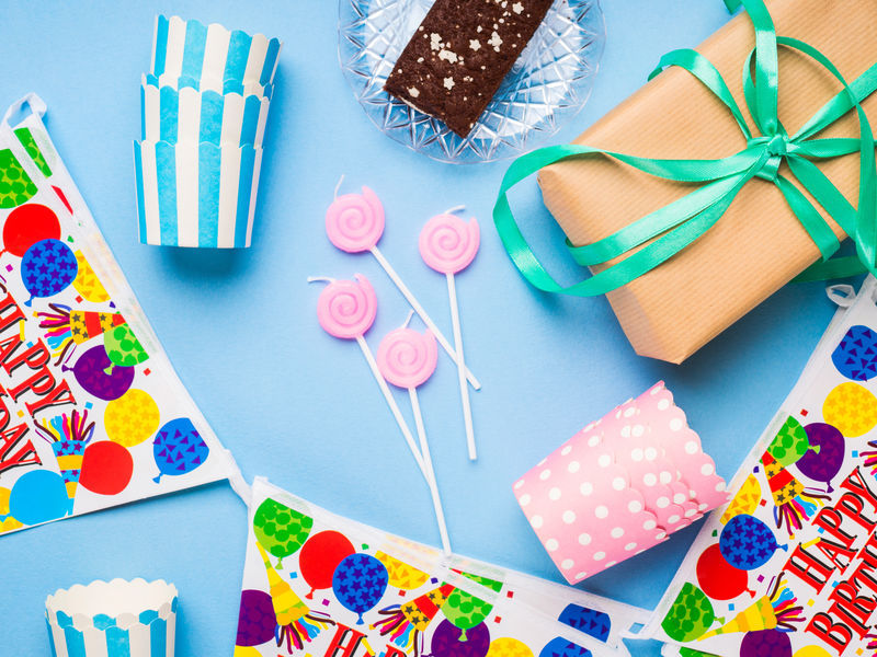 生日快乐派对用品平铺-蜡烛、礼品盒、装饰横幅、纸杯、巧克力蛋糕