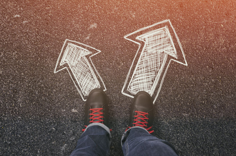 沥青路上的运动鞋-箭头指向两个方向-做决定和做选择的概念
