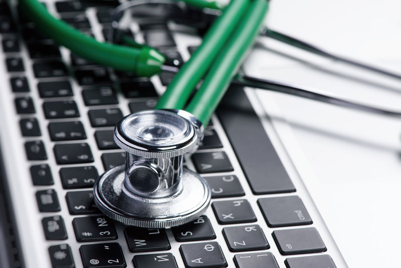 笔记本电脑键盘上的听诊器特写-医疗保健理念