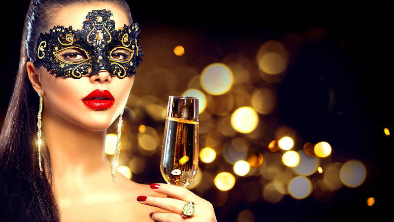 性感的模特女人-在派对上戴着威尼斯面具-在节日的光辉背景下喝着香槟-圣诞节和新年庆典-黑暗闪烁的背景
