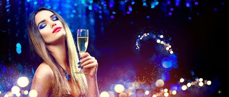 性感的模特女郎-在派对上喝着香槟-在假日里喝着香槟-背景是蓝色的-拥有完美时尚妆容的美女-圣诞节和新年庆祝活动