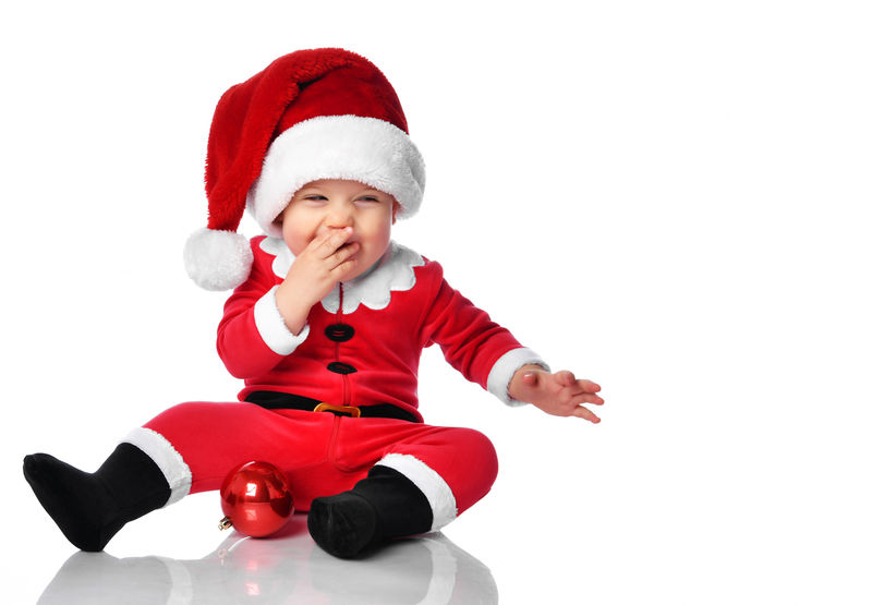 小男孩穿着圣诞老人的圣诞服装和帽子快乐地微笑着准备在白色背景下庆祝新年晚会