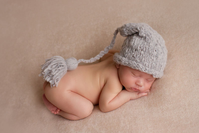 第一次拍照-新生儿-戴着灰色帽子的孩子-那孩子躺在米色毯子上