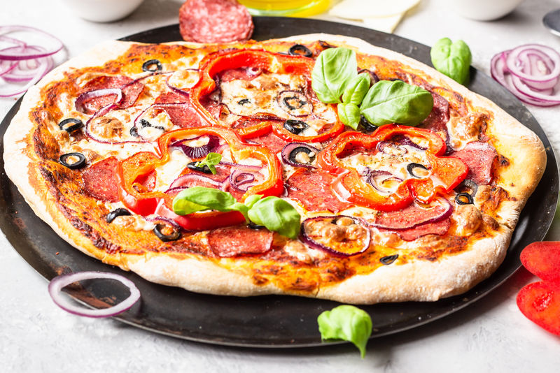 美味的披萨-配意大利腊肠、洋葱、胡椒、橄榄、马苏里拉奶酪和罗勒-自制辣香肠披萨