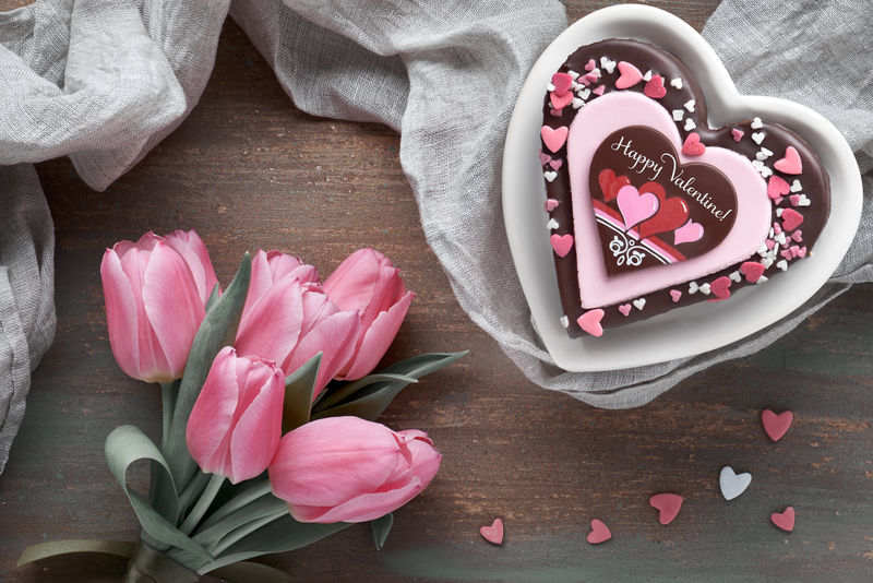 情人节蛋糕，上面写着“情人节快乐”和粉色郁金香