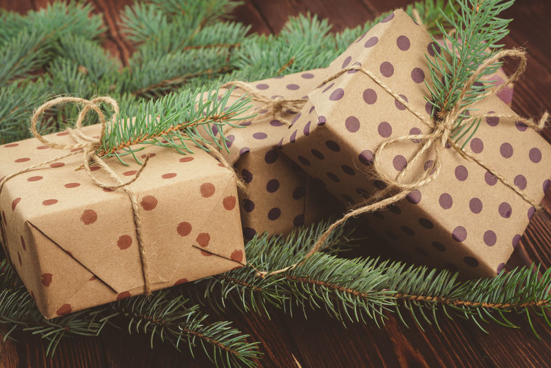 木制桌子上的圣诞礼物和松树枝，俯视图