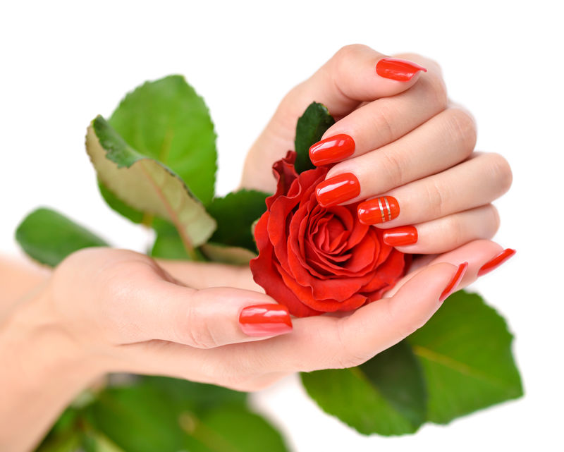 一个女人的手上有红色的指甲和白色的芭蕉上的红玫瑰