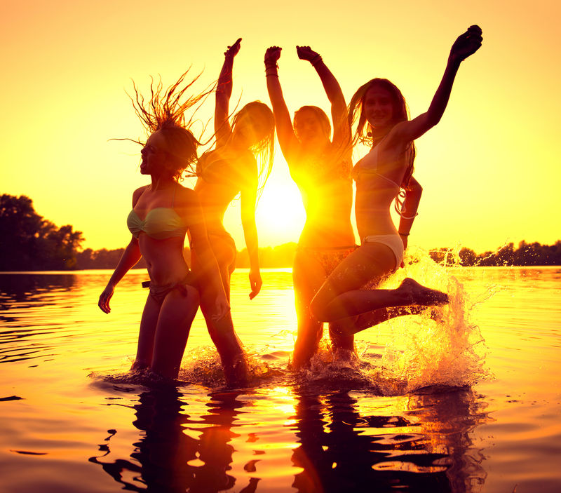 海滩派对。一群美丽的女孩在美丽的夏日日落中翩翩起舞。