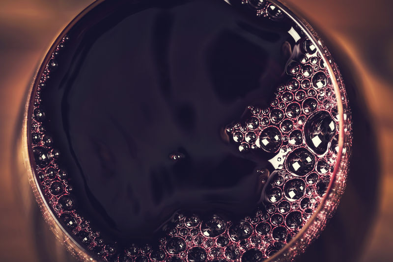 红酒放在酒杯里，背景是木制的，以一个中心为中心