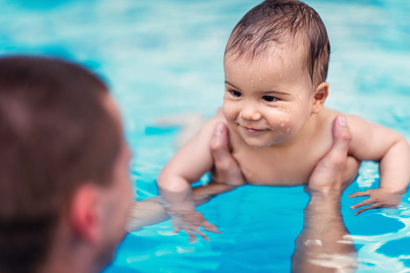 游泳池里微笑的男婴