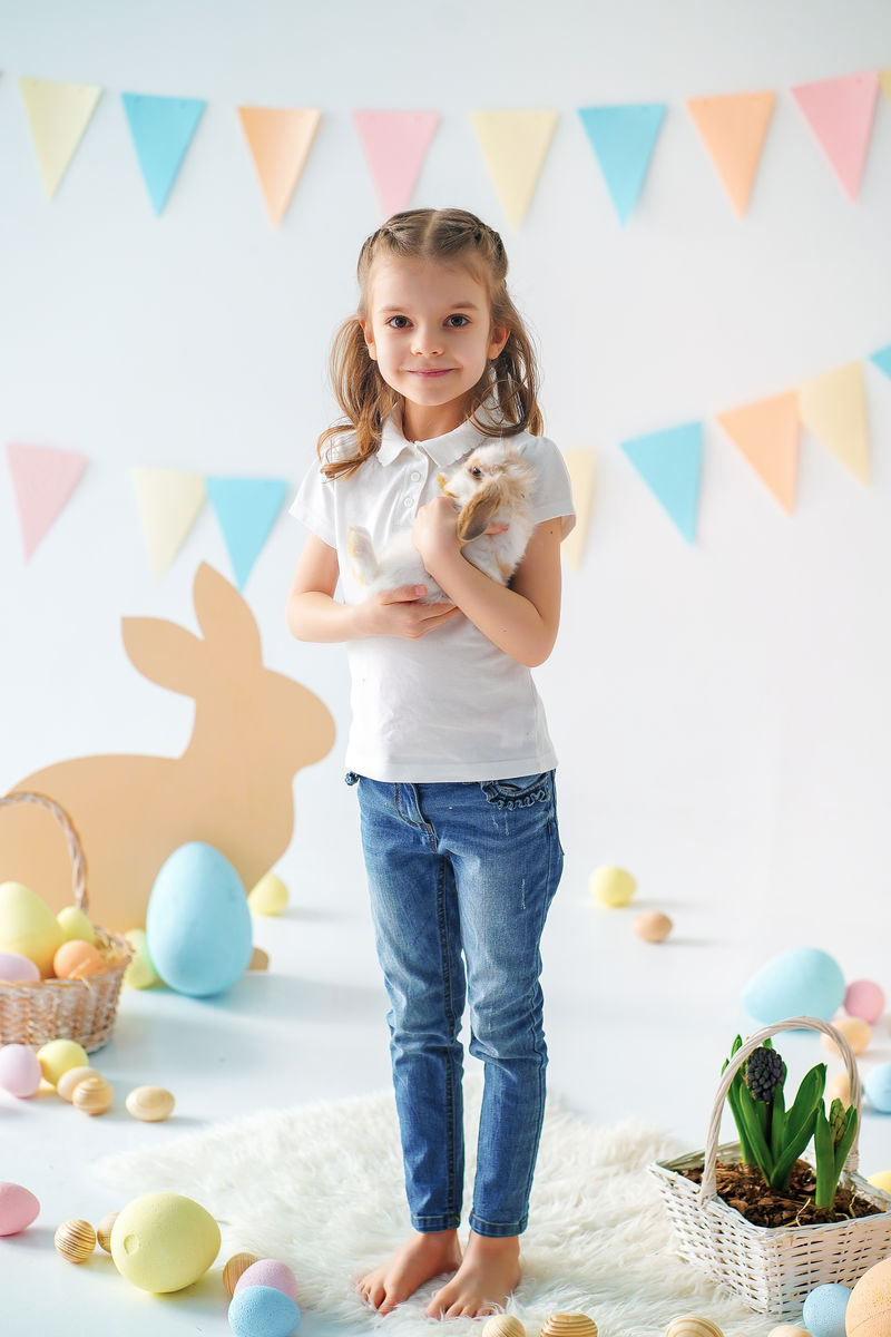 带兔子的女孩。快乐的小女孩抱着可爱的毛茸茸的兔子。与复活节兔子的友谊。春天与美丽的小女孩和她的兔子合影。女孩抱着一只可爱的小兔子