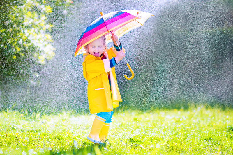 滑稽的小孩在雨中玩伞