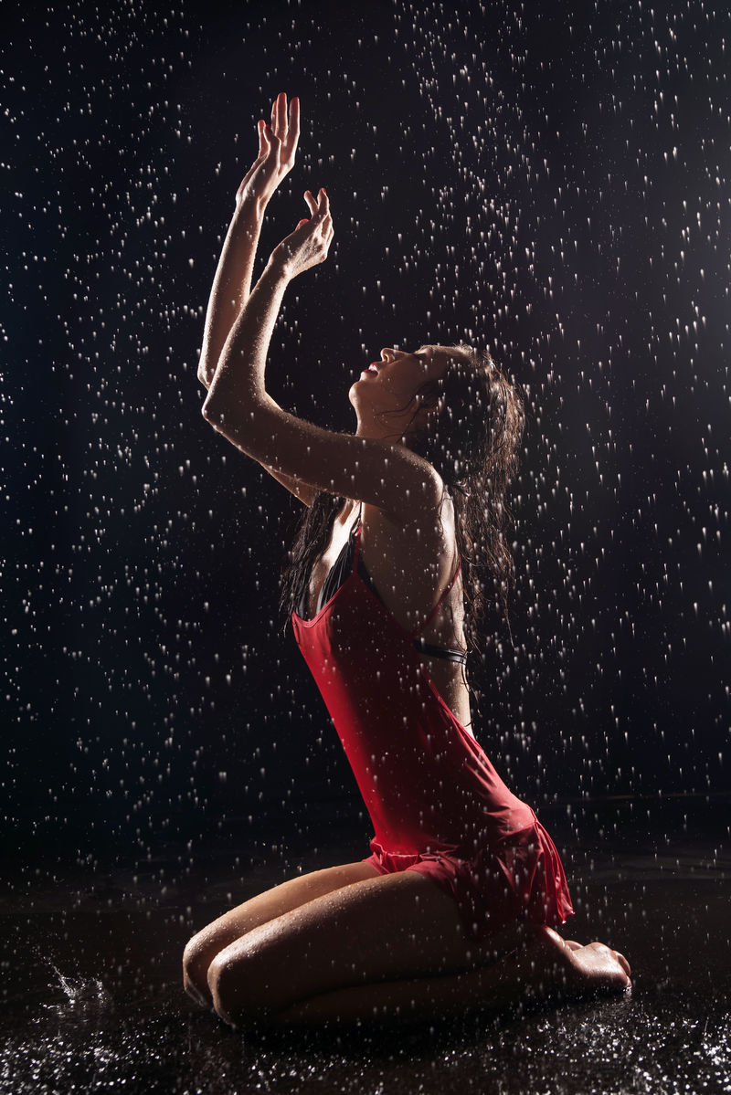 在水滴下穿着红色短裙的女人。雨