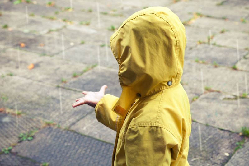 穿着黄色雨衣玩雨滴的小孩