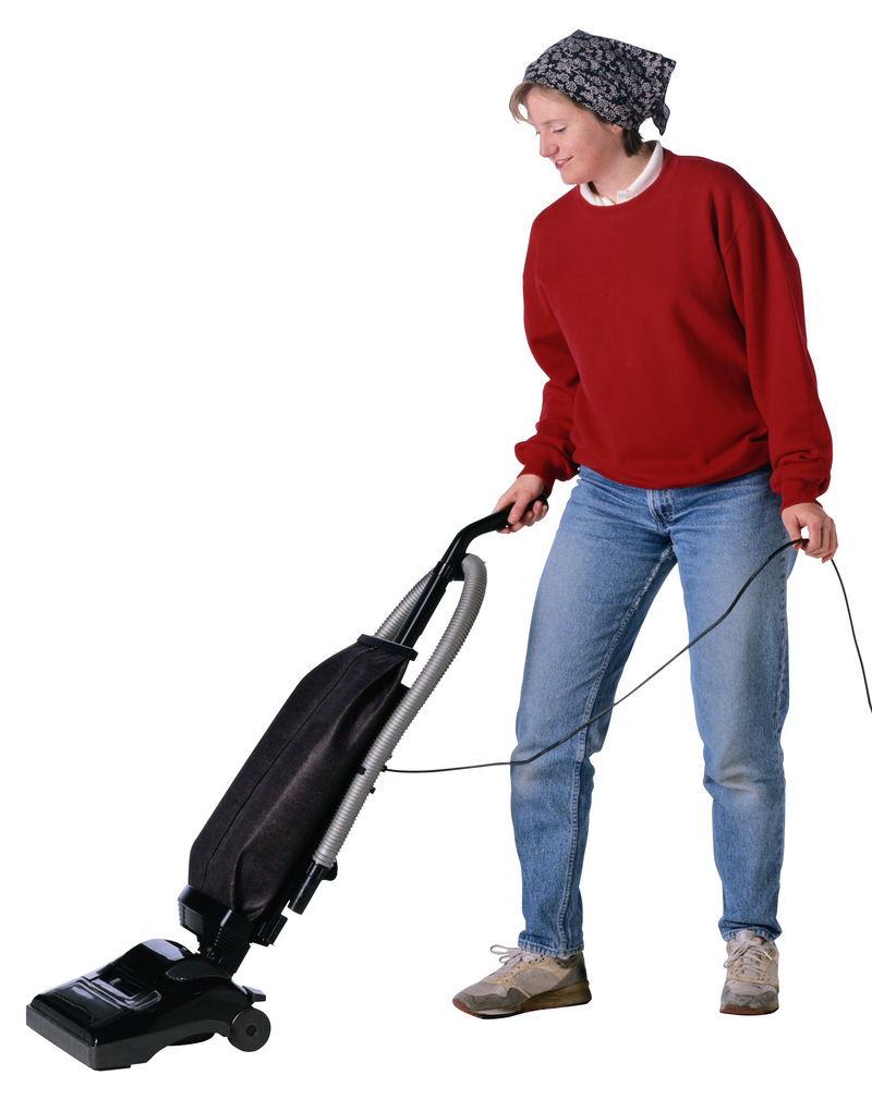 年轻快乐的女人用吸尘器打扫家里的地板