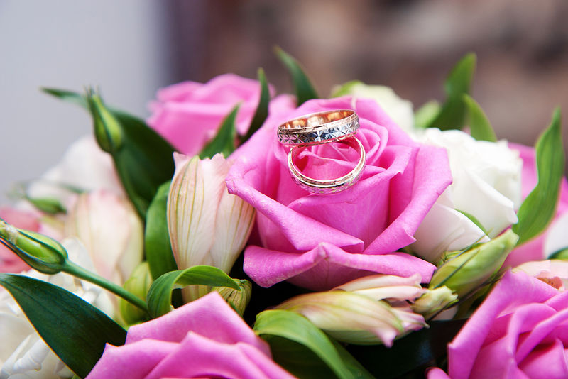 新娘花束背景上的两枚金结婚戒指