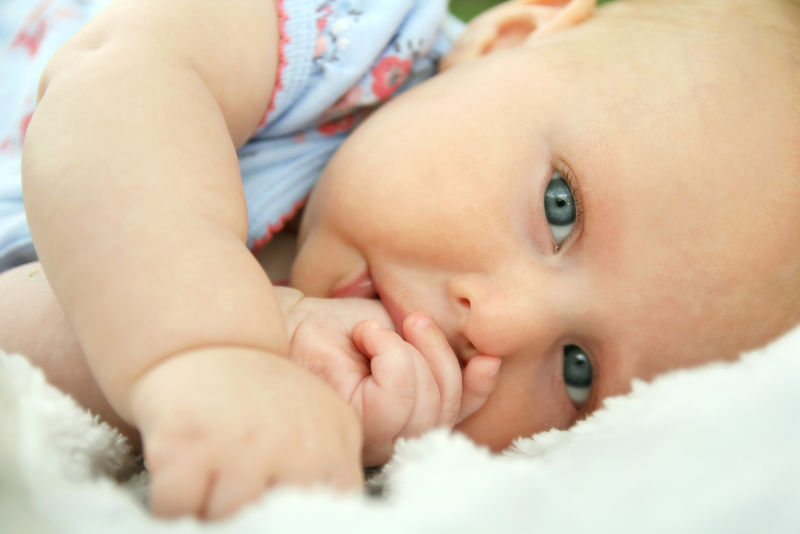 新生女婴躺在地上吮吸拇指