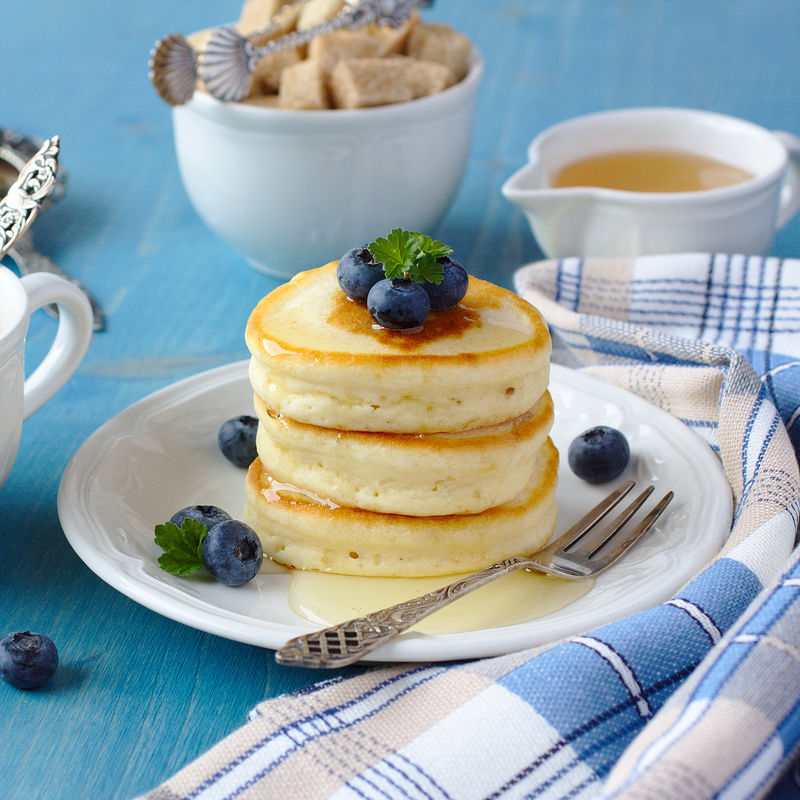 早餐桌上有一叠加蜂蜜和蓝莓的苏格兰薄饼