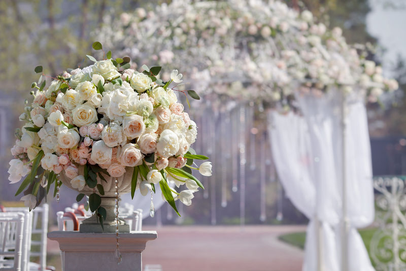 婚礼拱门背景上花瓶中美丽的玫瑰花束。为婚礼而设的美丽婚礼。