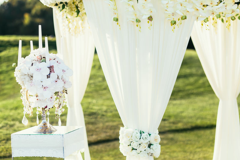 用鲜花和сANDLE装饰在阳光明媚的一天，在婚礼上拱