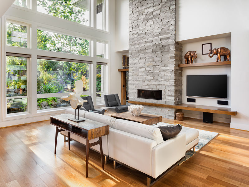 漂亮的客厅，配有硬木地板、壁炉和大窗户，可以看到茂密的植被，位于新的豪华住宅中