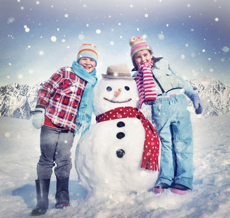 小女孩和男孩户外冬季雪人概念