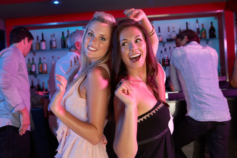 两个年轻女子在繁忙的酒吧里玩得很开心
