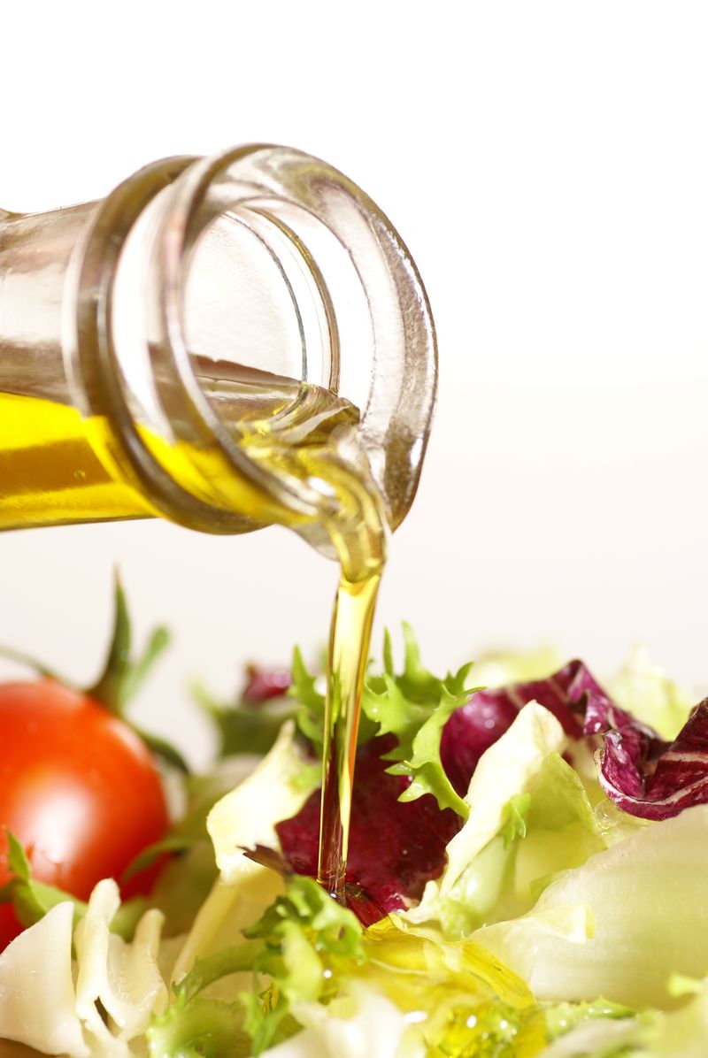 用倒入橄榄油和蔬菜沙拉的瓶子的特写镜头